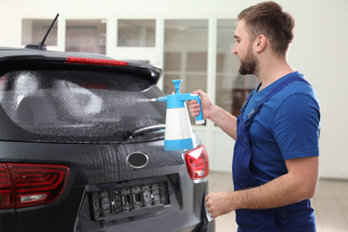 Photo of Worker spraying water onto car window before tinting