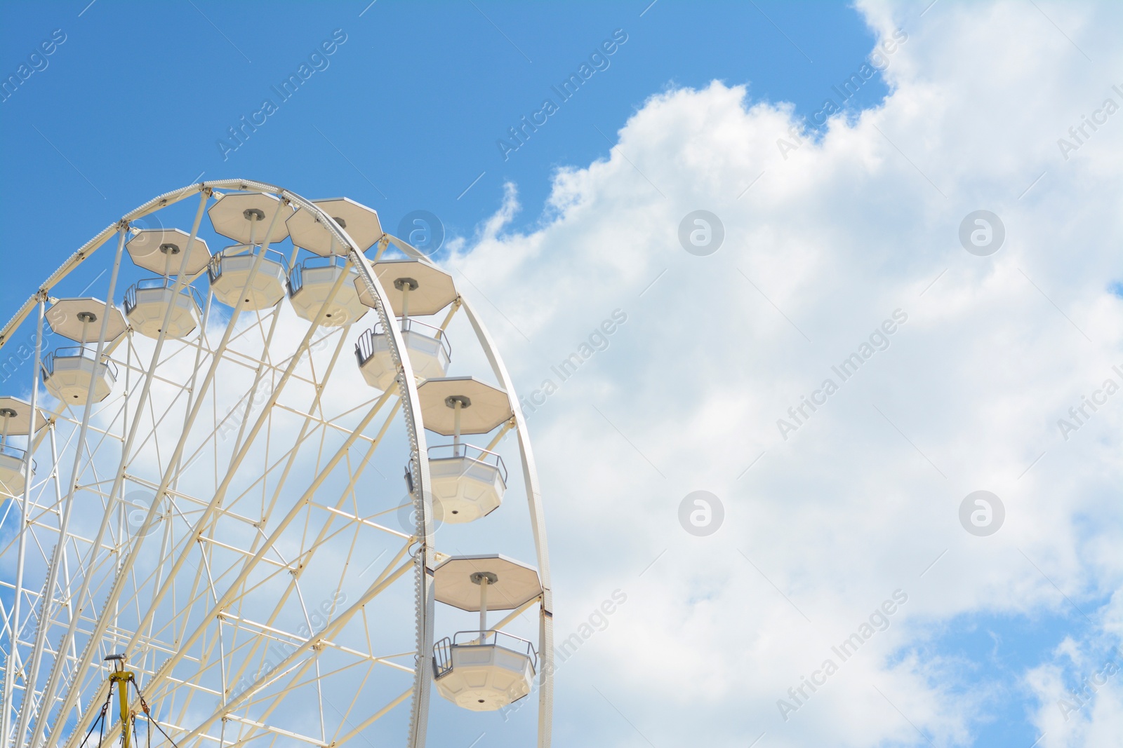 Photo of Large observation wheel against blue cloudy sky, space for text