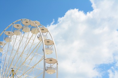 Large observation wheel against blue cloudy sky, space for text
