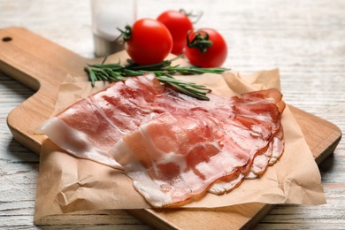 Photo of Board with raw bacon rashers on table