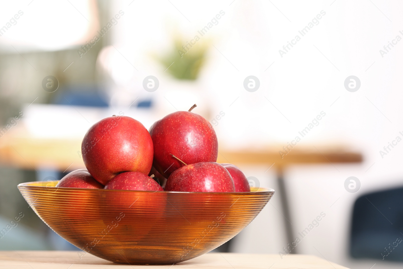 Photo of Bowl with sweet red apples on table in room, space for text