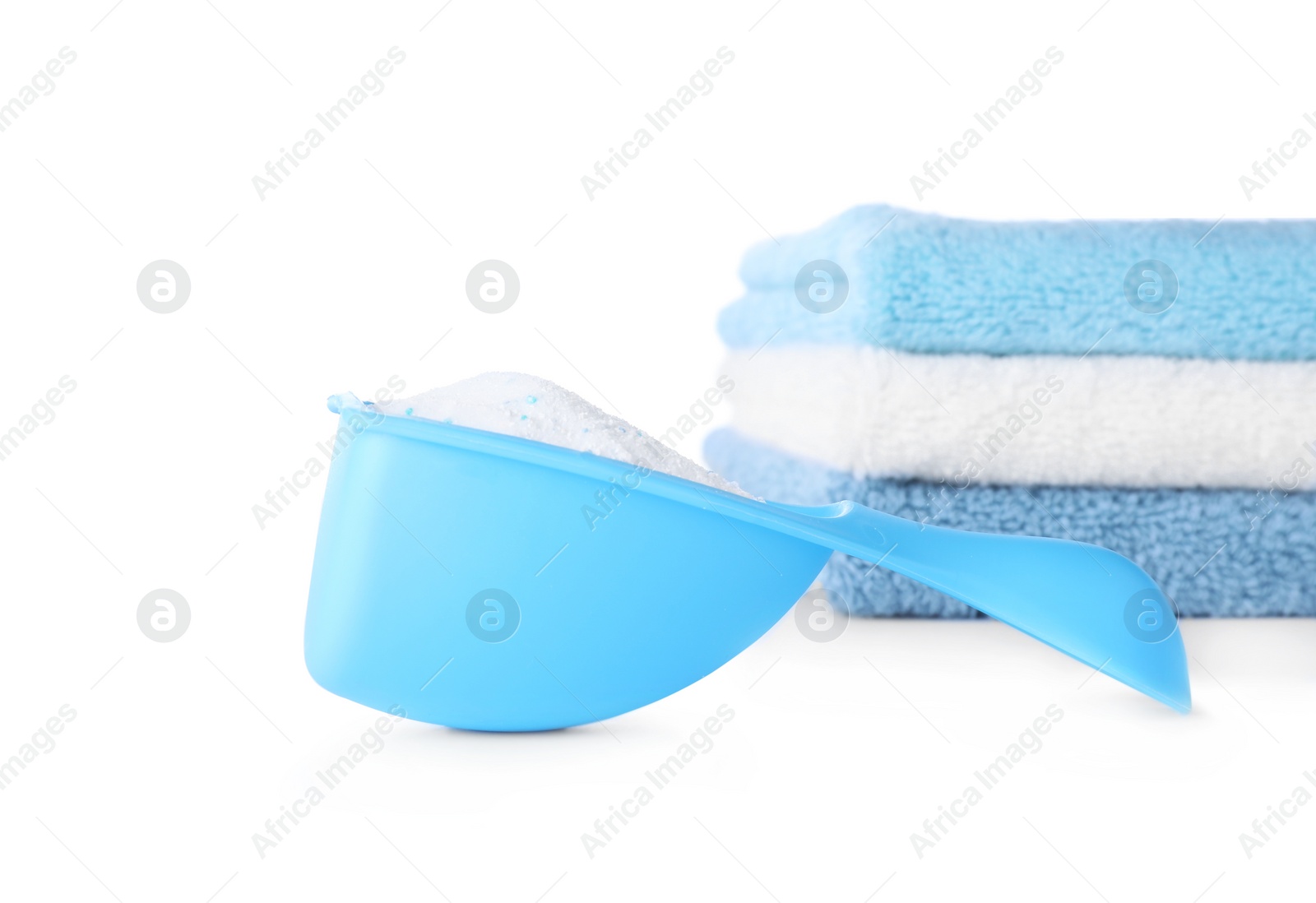 Photo of Laundry detergent in plastic measuring scoop and towels on white background