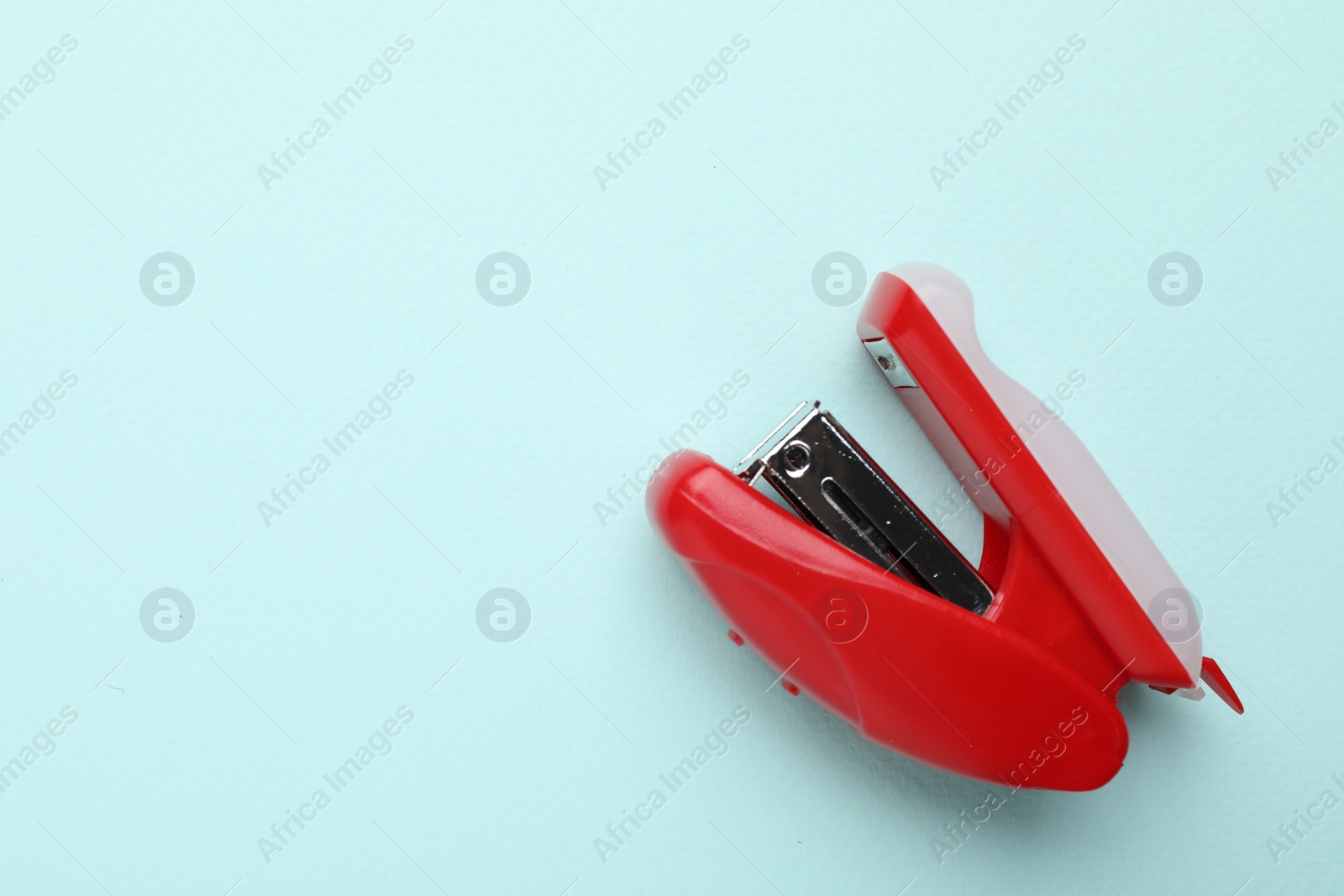 Photo of One red stapler on light blue background, top view. Space for text