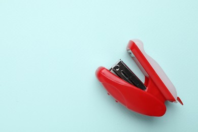 One red stapler on light blue background, top view. Space for text