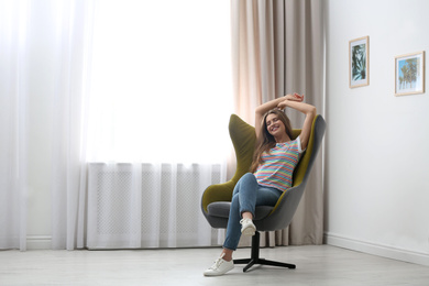 Photo of Young woman resting in armchair at home. Space for text