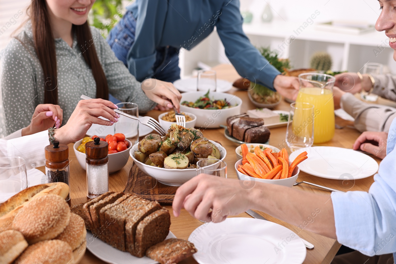 Photo of Friends eating vegetarian food at wooden table indoors, closeup