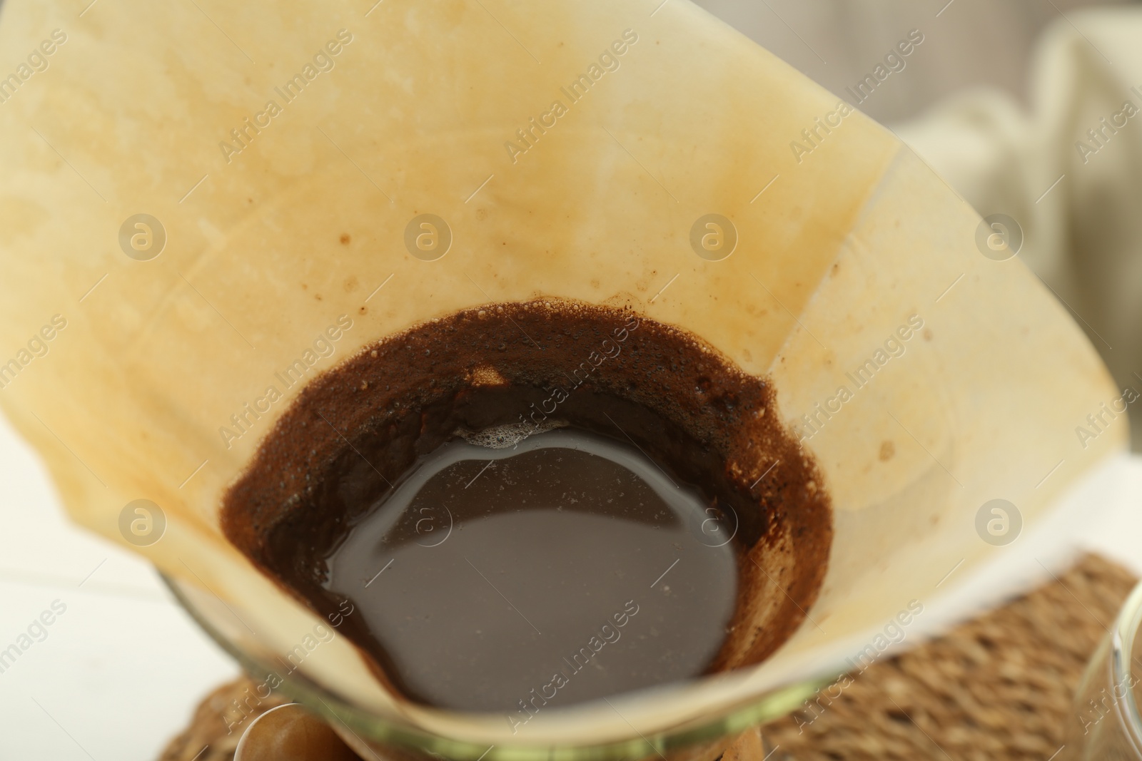 Photo of Paper filter with aromatic drip coffee in glass chemex coffeemaker, closeup