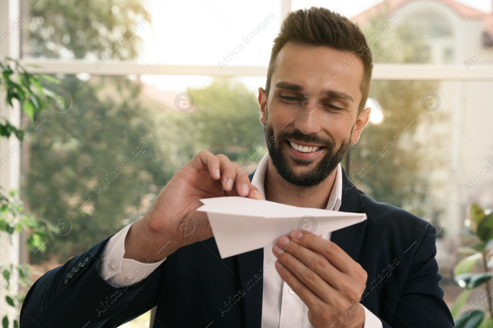 Photo of Handsome businessman playing with paper plane in office