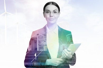 Multiple exposure of businesswoman with tablet, wind turbines and solar panels installed outdoors. Alternative energy source