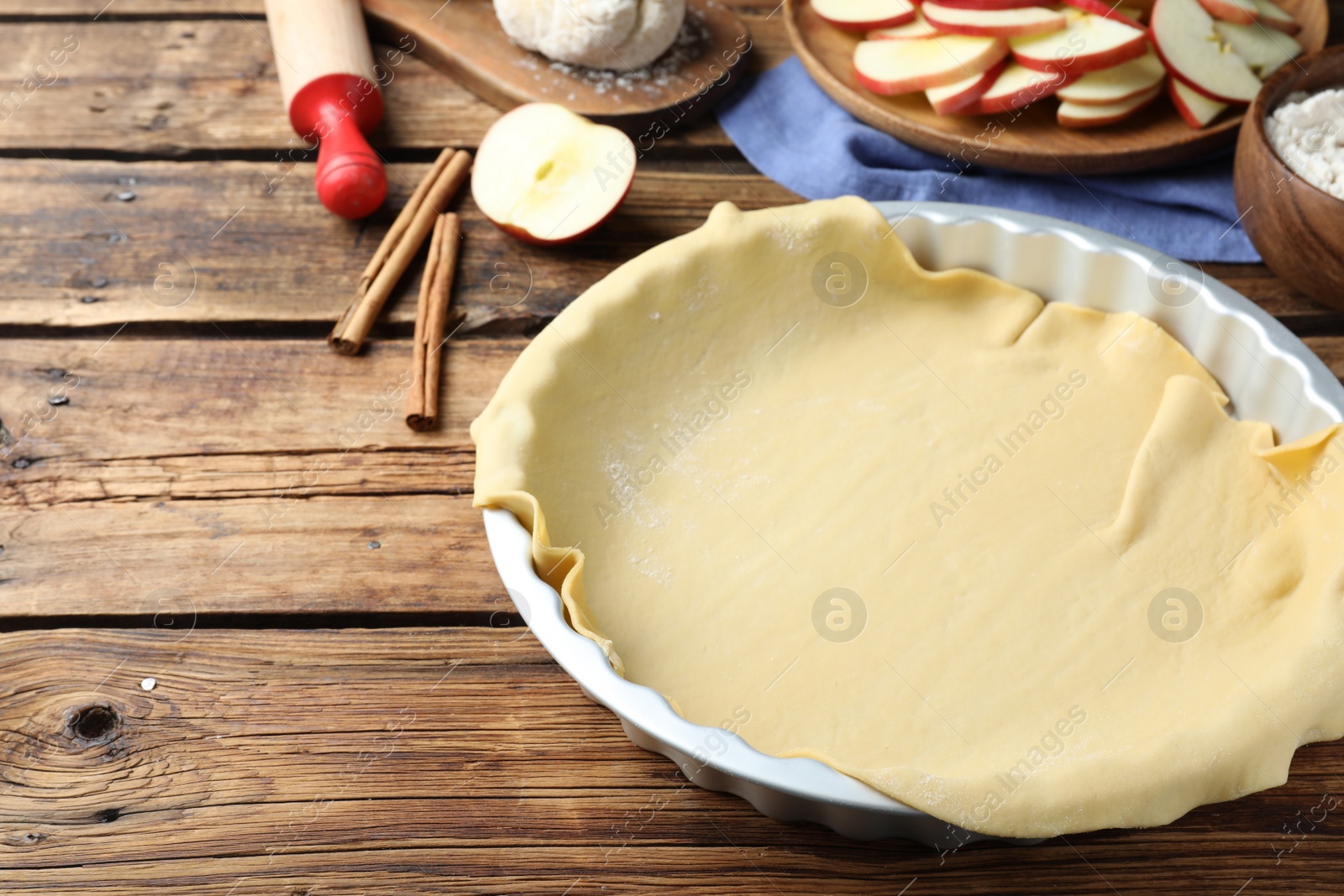 Photo of Raw dough and ingredients on wooden table, space for text. Baking apple pie