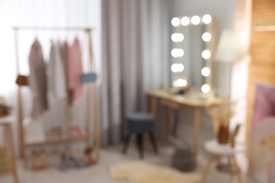 Blurred view of makeup room with stylish mirror, dressing table and chair