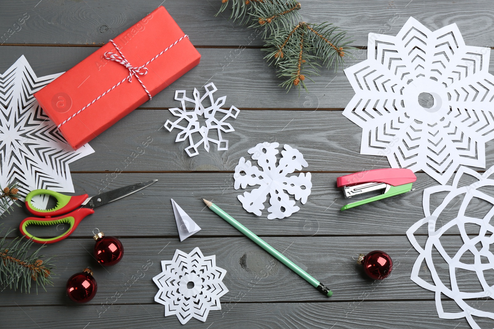 Photo of Flat lay composition with paper snowflakes on grey wooden table