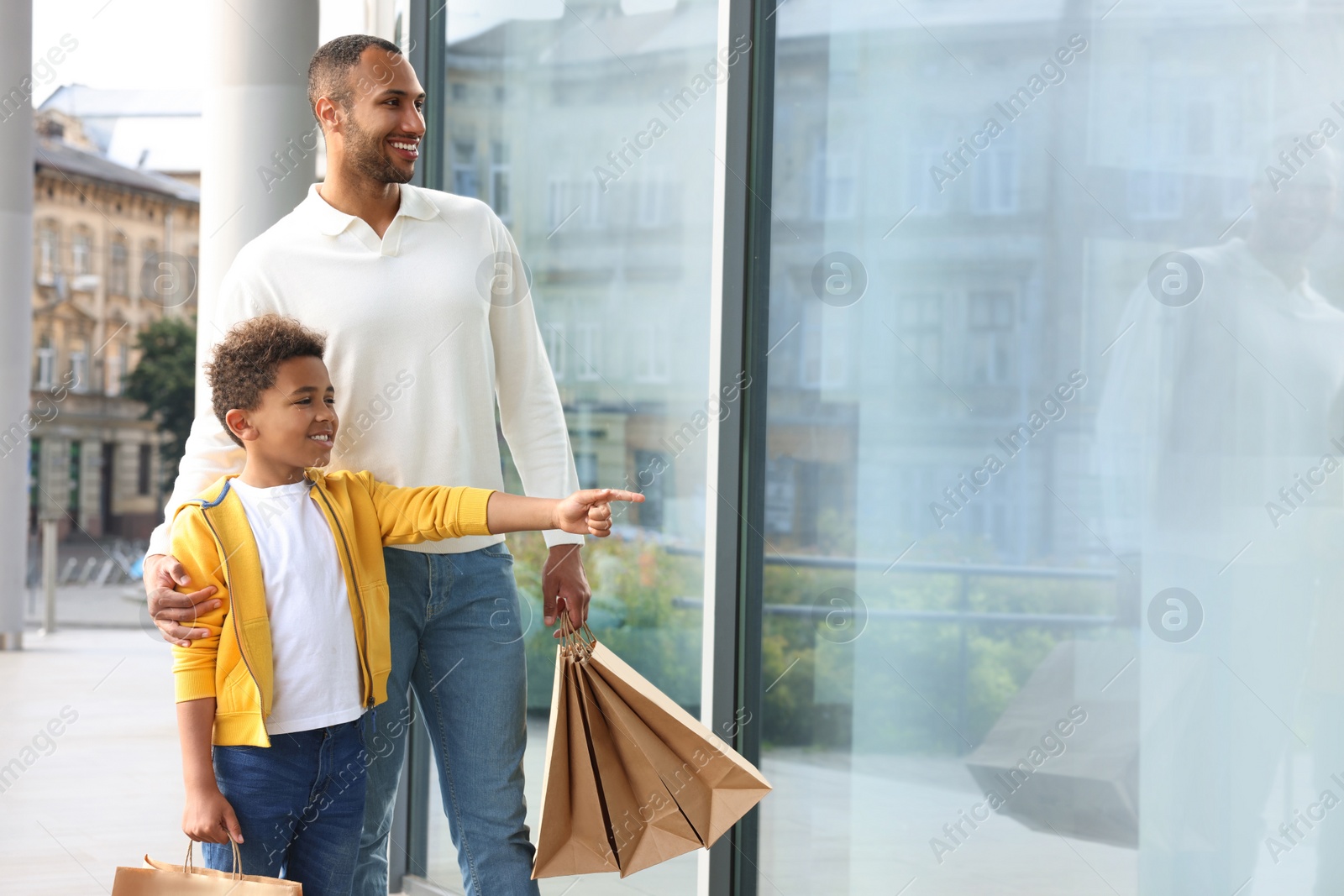 Photo of Family shopping. Happy father and son with purchases near mall outdoors