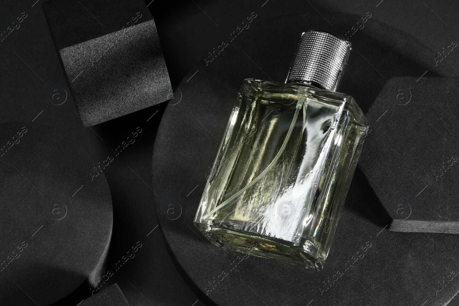 Photo of Stylish presentation of luxury men`s perfume in bottle on black background, top view. Space for text