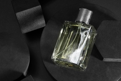 Photo of Stylish presentation of luxury men`s perfume in bottle on black background, top view. Space for text