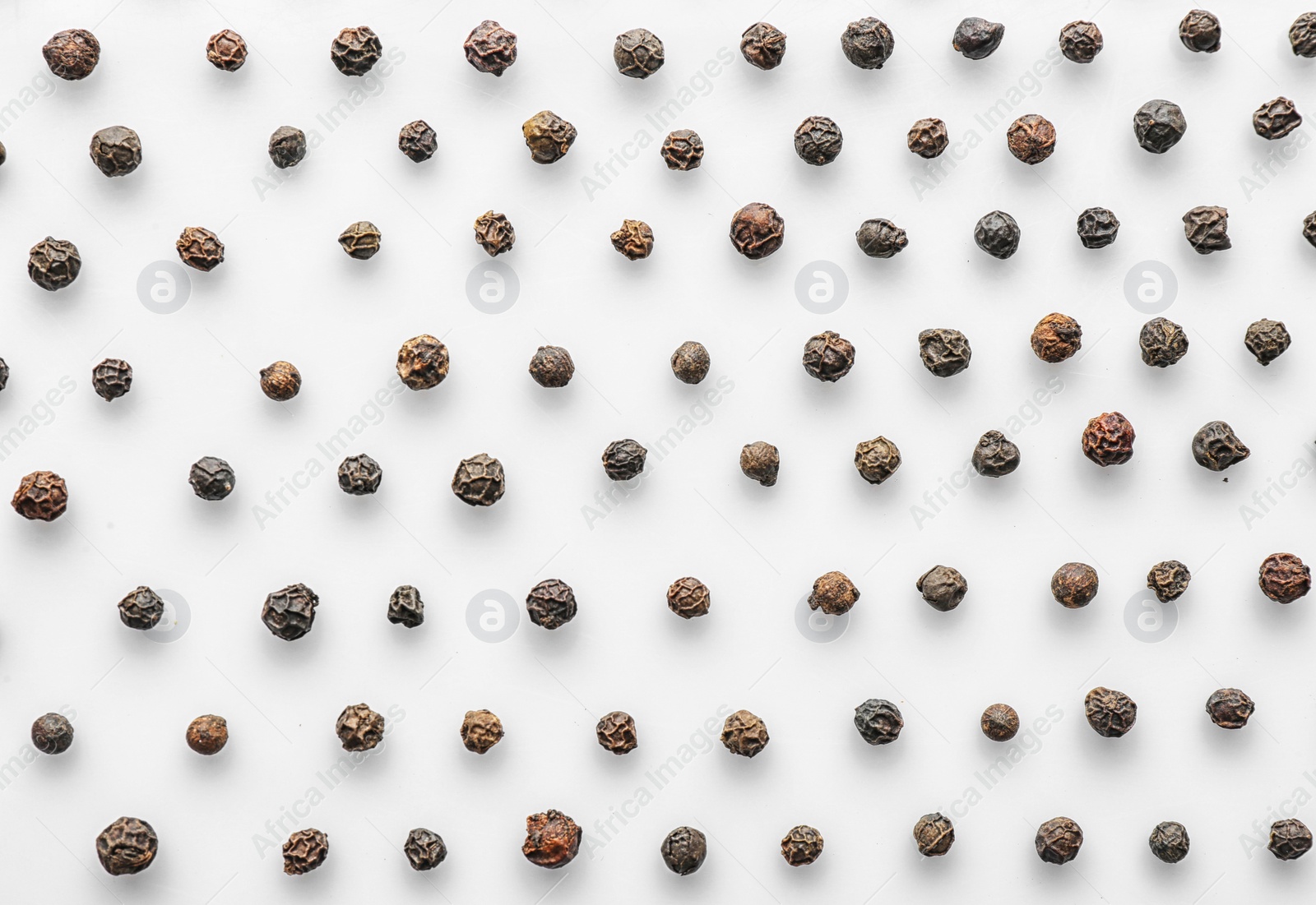 Photo of Black pepper grains on white background, top view