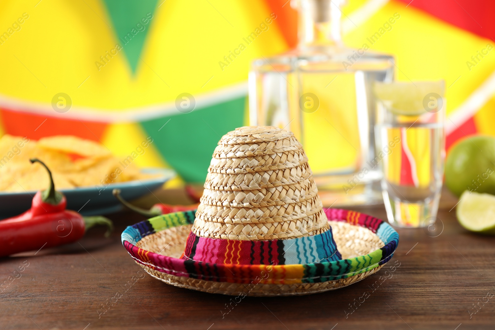 Photo of Mexican sombrero hat and tequila on wooden table