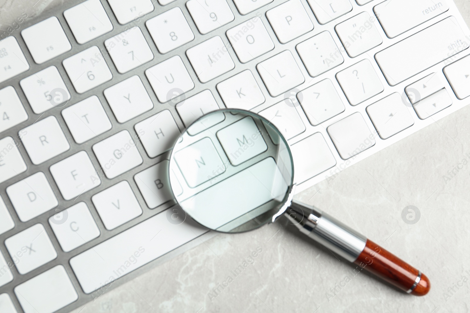 Photo of Magnifying glass and computer keyboard on light grey marble table, top view. Search concept