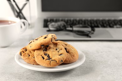 Chocolate chip cookies on light gray table at workplace