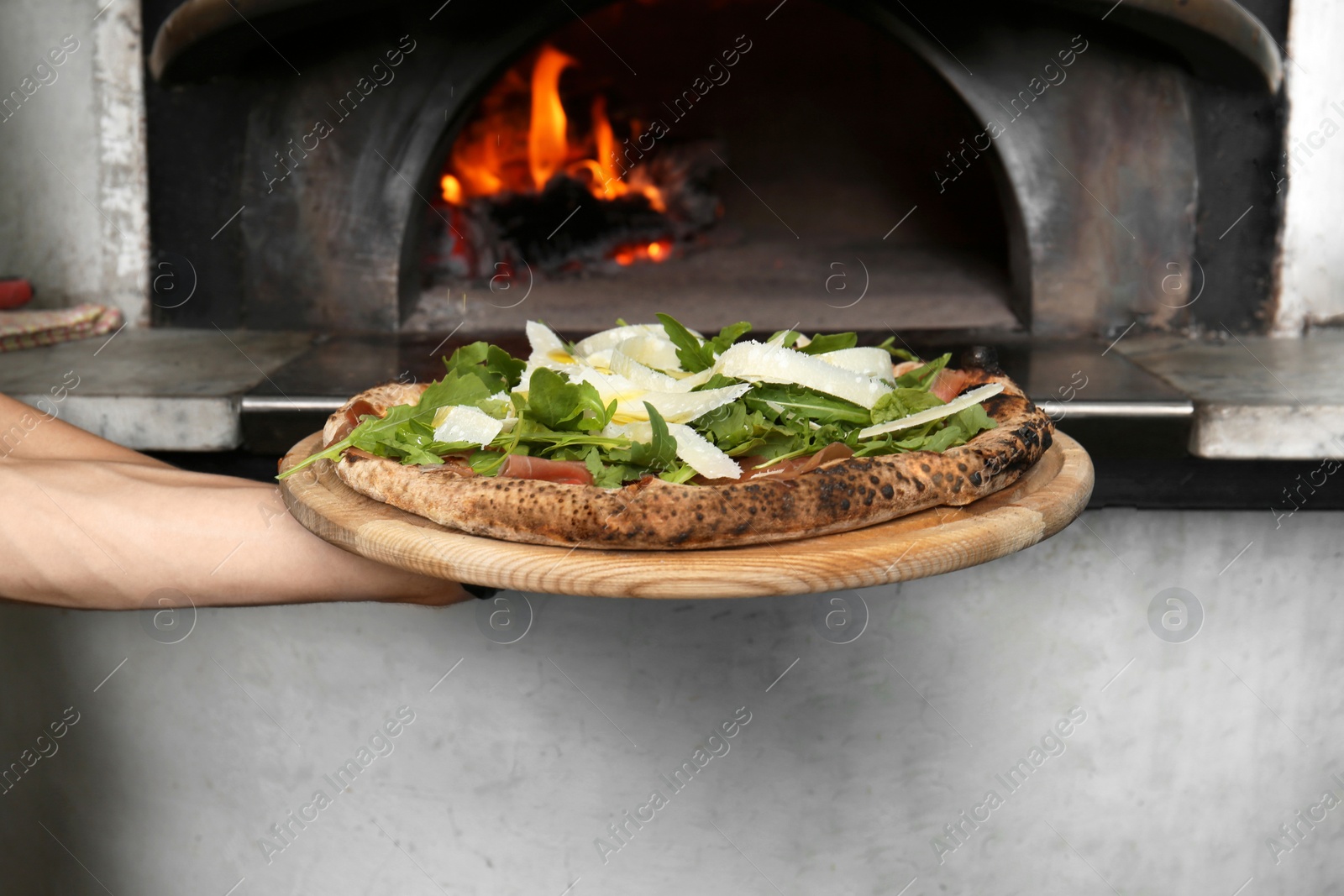 Photo of Professional chef holding tasty Italian pizza near oven in restaurant, closeup