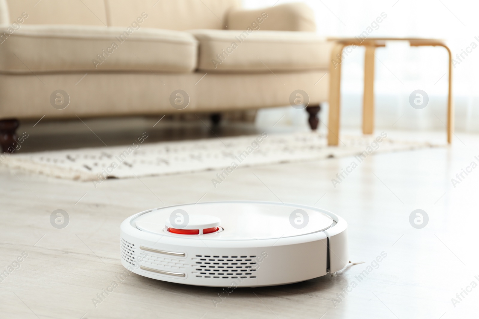 Photo of Modern robotic vacuum cleaner on floor in living room. Space for text