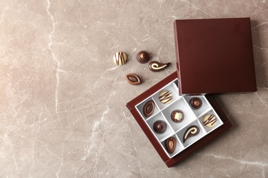 Photo of Box with different tasty chocolate candies on table, top view