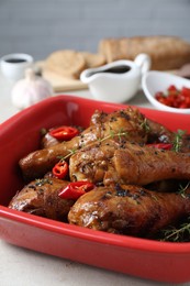 Photo of Chicken legs glazed in soy sauce with black sesame, chili pepper and thyme on light table, closeup