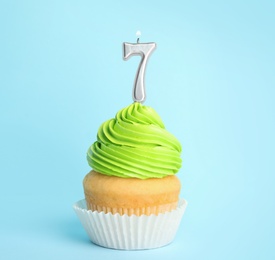 Photo of Birthday cupcake with number seven candle on blue background