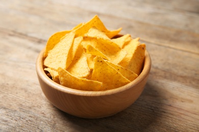 Photo of Tasty mexican nachos chips in bowl on wooden table