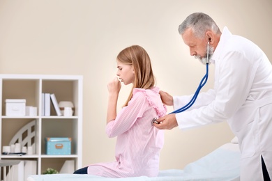 Photo of Doctor examining coughing teenage girl at clinic