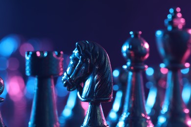 Photo of Chess pieces in color light against blue background, closeup