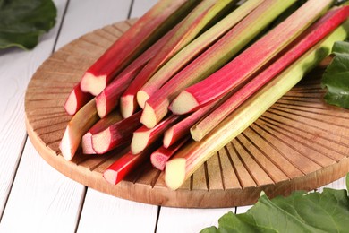 Many cut rhubarb stalks on white wooden table, closeup