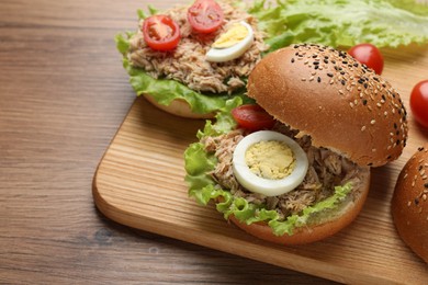 Photo of Delicious sandwiches with tuna, boiled egg and vegetables on wooden table, space for text