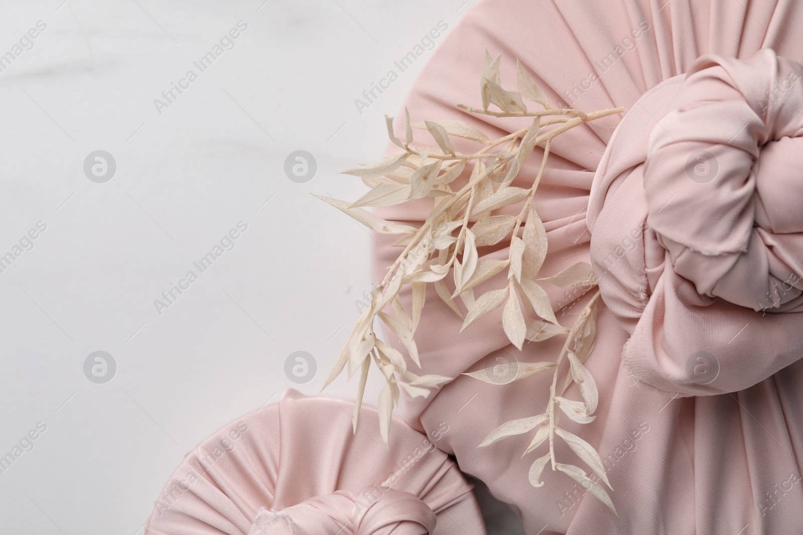 Photo of Furoshiki technique. Gifts packed in pink fabric and dried branches on white marble table, flat lay. Space for text