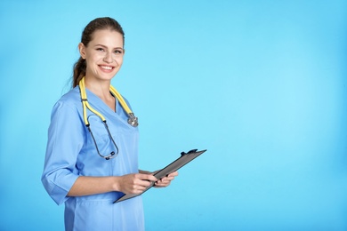 Photo of Portrait of young medical assistant with stethoscope and clipboard on color background. Space for text