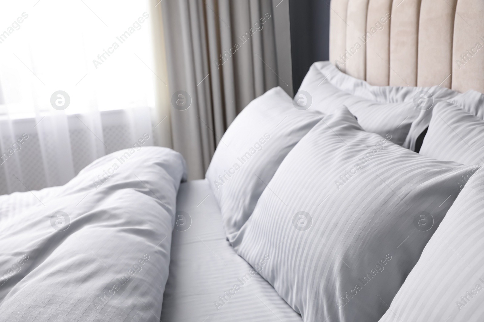 Photo of Comfortable bed with soft blanket and pillows indoors, closeup