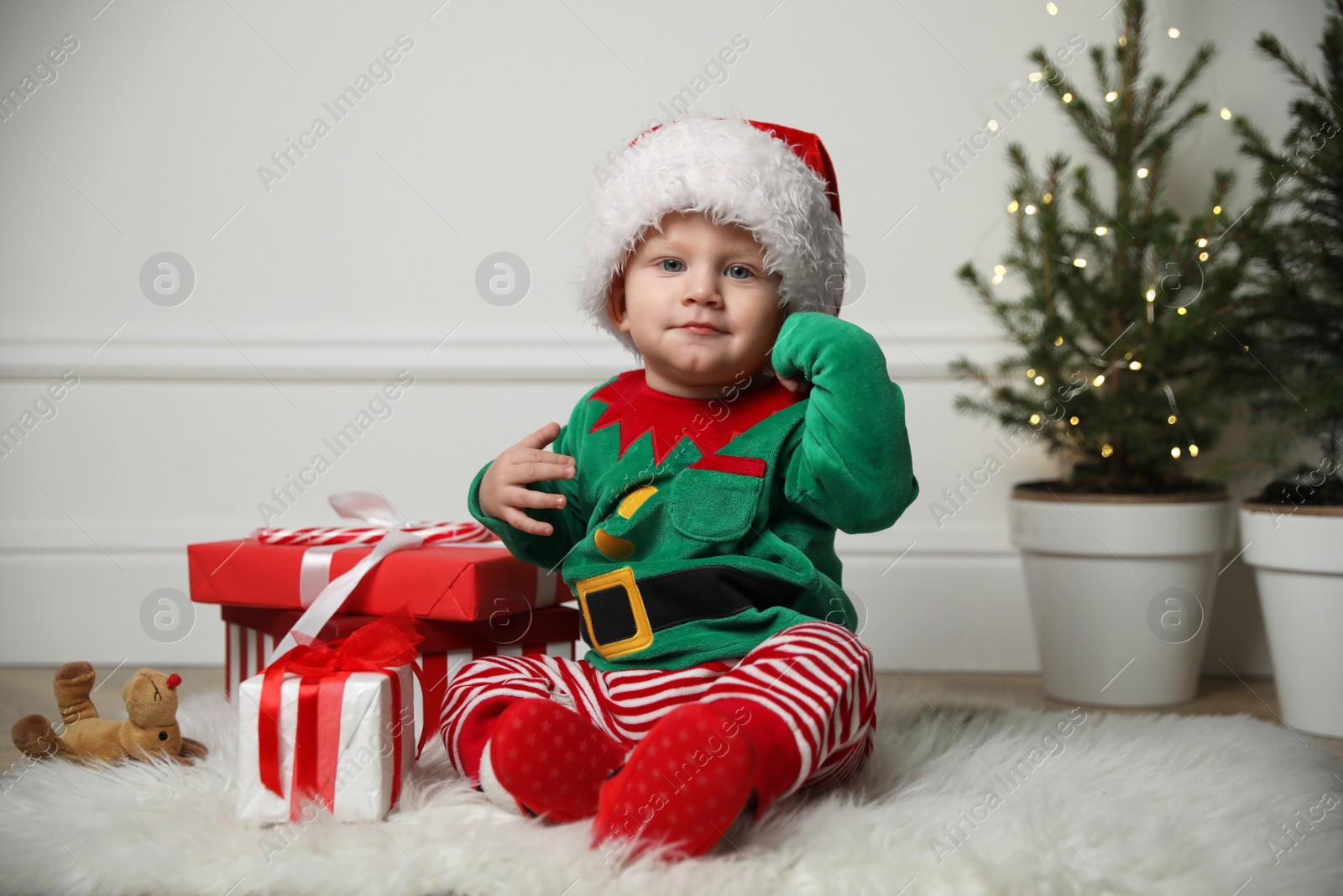 Photo of Baby in cute Christmas outfit with gifts at home