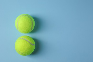 Photo of Two tennis balls on light blue background, top view. Space for text