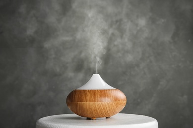 Photo of Modern essential oil diffuser on white table against grey background