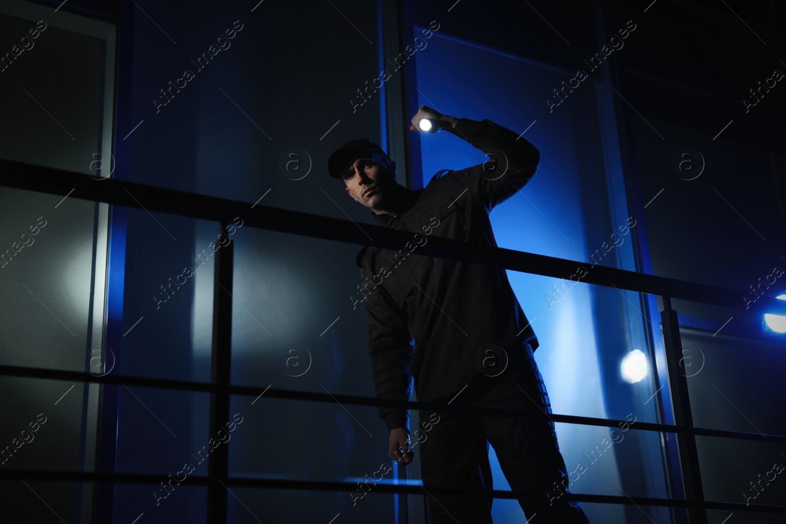 Photo of Male security guard with flashlight in dark room