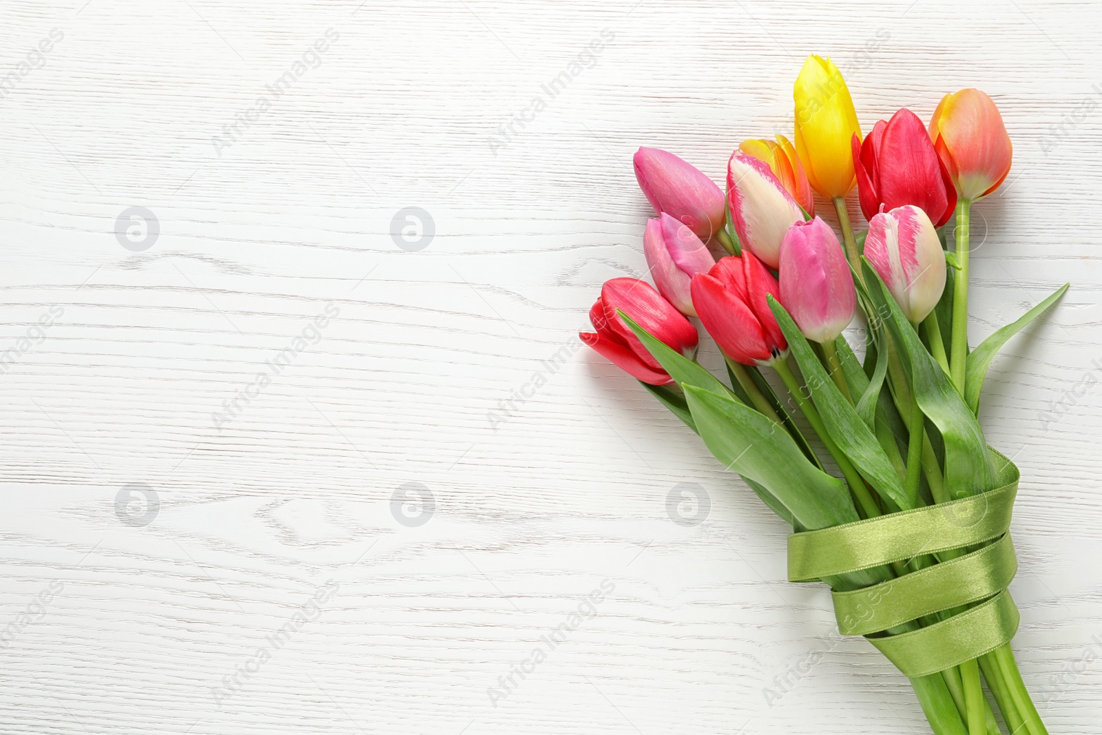 Photo of Beautiful bouquet of spring tulip flowers on wooden background, top view. Space for text