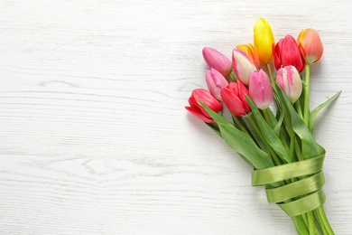 Beautiful bouquet of spring tulip flowers on wooden background, top view. Space for text