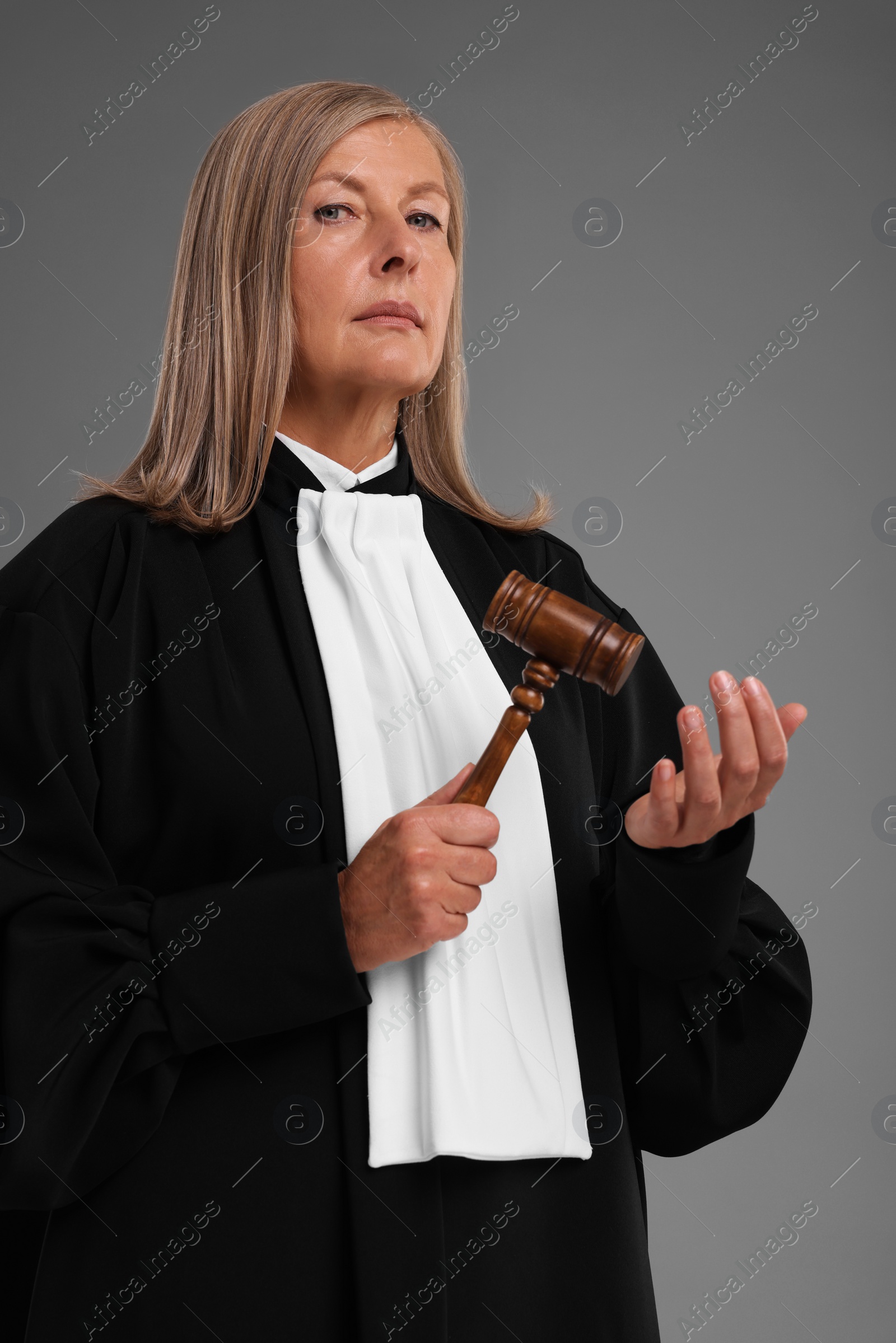 Photo of Senior judge with gavel on grey background