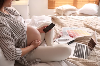 Photo of Pregnant woman working on bed at home, closeup. Maternity leave