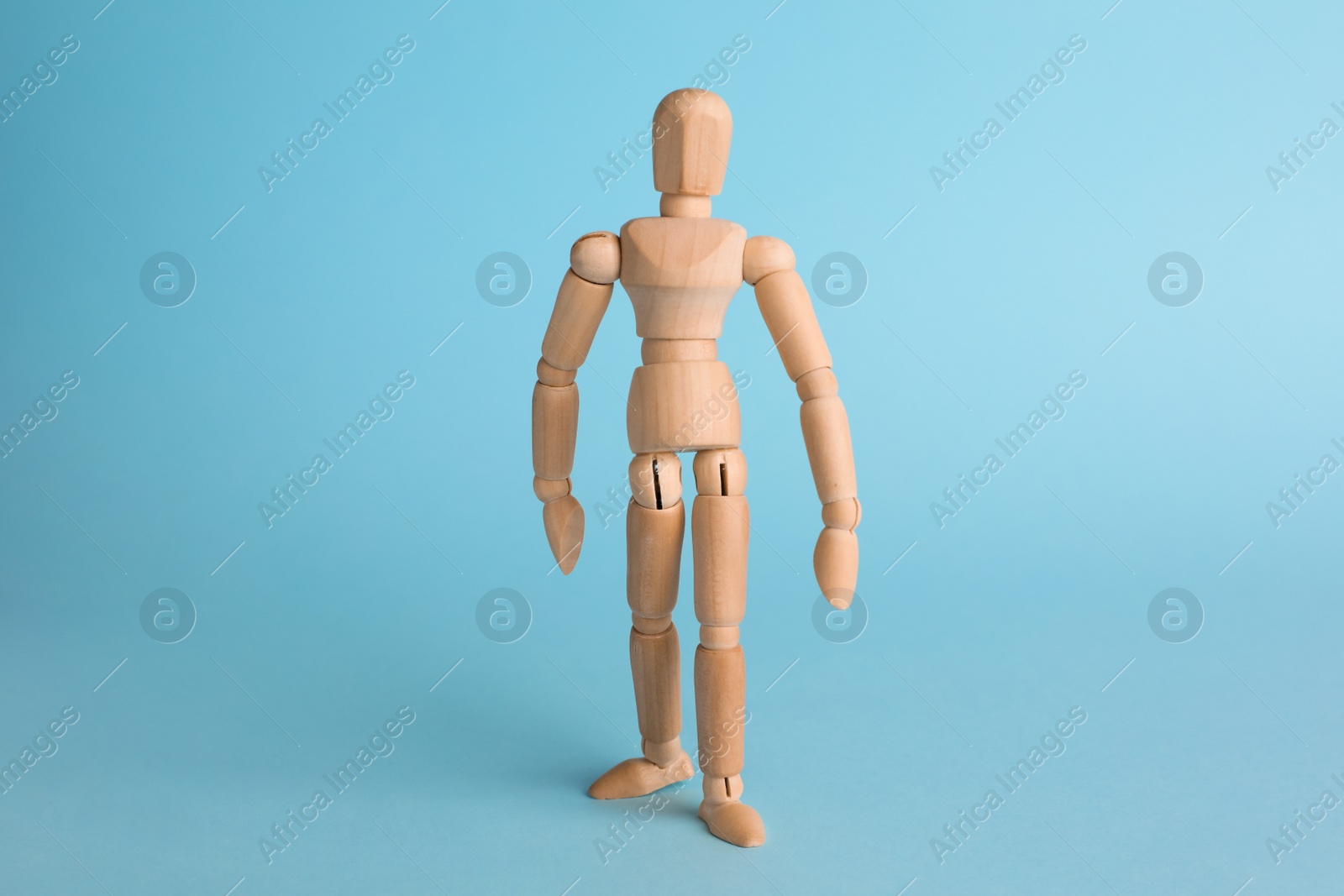 Photo of Wooden human model on light blue background. Mini mannequin