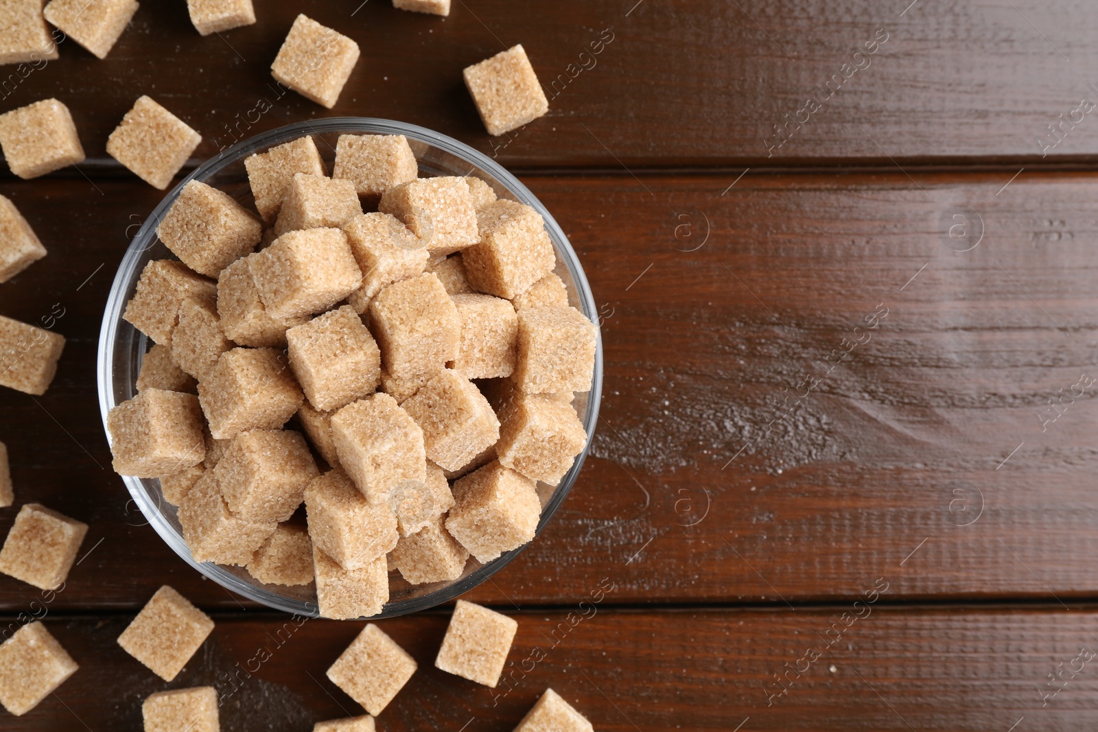 Photo of Brown sugar cubes on wooden table, flat lay. Space for text