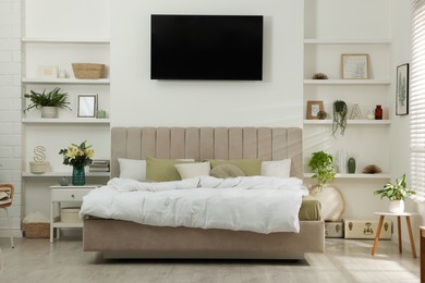 Stylish bedroom interior with houseplants, tv and decorative elements