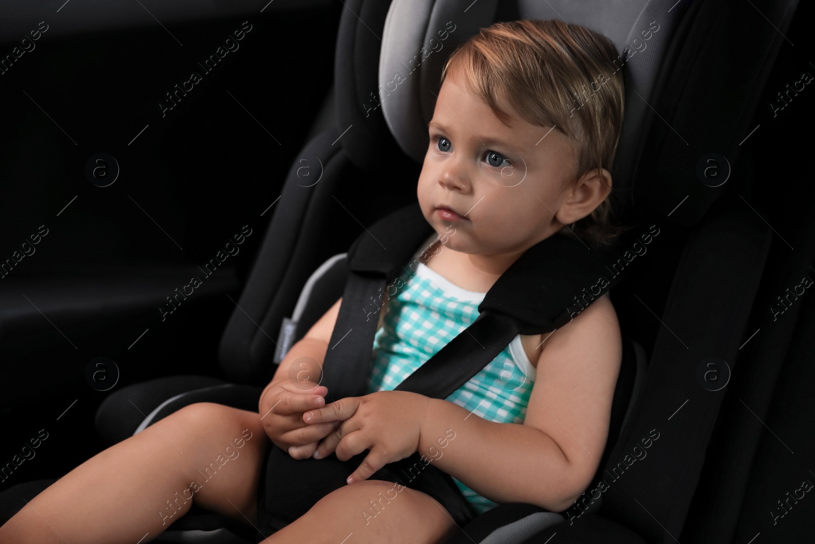 Photo of Cute little girl sitting in child safety seat inside car