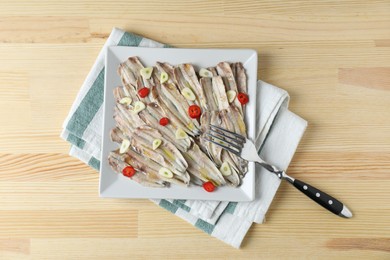 Photo of Tasty pickled anchovies with garlic, chili pepper and fork on wooden table, top view