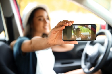 Happy young woman taking selfie in car